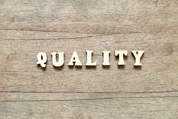 Letter block in word quality on wood background