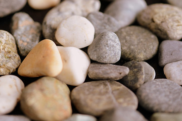 Scattered pebble stones on a dark background close up