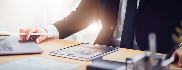 Businessman planner a schedule in the calendar on digital tablet and hands press computer laptop at office.