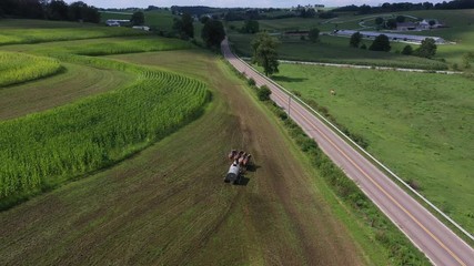 Aerial Ohio Amish four horse team fertilizing crops overhead. Settled 1700's as pioneer religious settlement. Old Mennonite town. Rural farm. Farming religious community. Horse driven equipment.