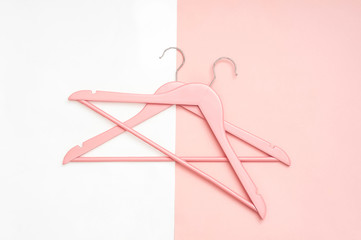 Stylish pink wooden clothes hangers on a white and pink background. Pastel colors. Clothing storage device.  Top view. Flat lay