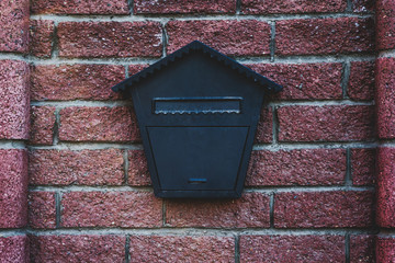 old black steel mailbox on brick wall