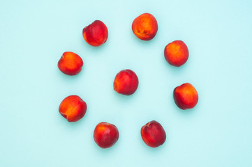 Bright red peaches nectarine in the shape of a circle on a blue background. Top view. Flat lay