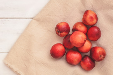Ripe red peaches on a beige tablecloth, white wooden boards. Vitamins Healthy eating.  Peaches nectarine. Top view. Flat lay.