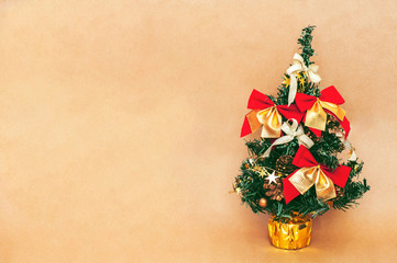 Christmas tree decorated with red golden bows and New Year's toys on a yellow beige background. New Year holiday background. Space