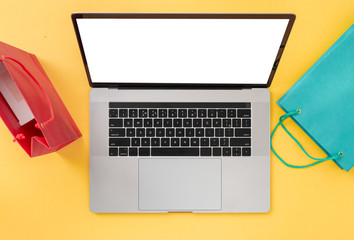 Home Internet Shopping Ecommerce Laptop with blank screen on a yellow background with bags top view