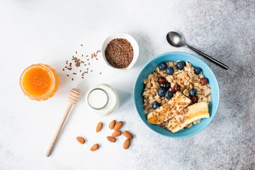 Oatmeal or breakfast oats porridge with fruits, flax seeds, honey in a bowl. Table top view. Healthy breakfast food ingredients, clean eating concept