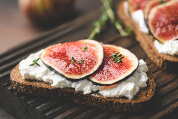 Toast with ricotta cheese and figs on wooden cutting board. Vertical orientation