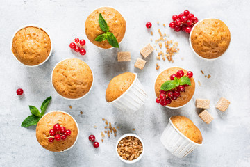 Vegan homemade muffins decorated with red berries and mint leaf on bright grey concrete background. Top view. Homemade tasty muffins