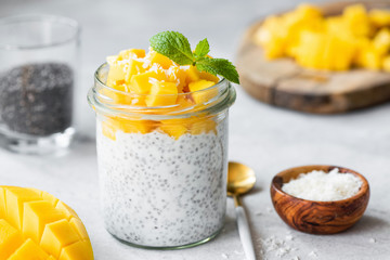 Chia seed pudding with mango cubes and coconut in glass jar. Closeup view. Vegan vegetarian food, clean eating concept