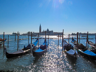 Fototapeta na wymiar Gondolas near Saint Mark square, Venice, Italy. Scenic view on Venetian landmarks - water surface and seafront with famous traditional Italian boats.