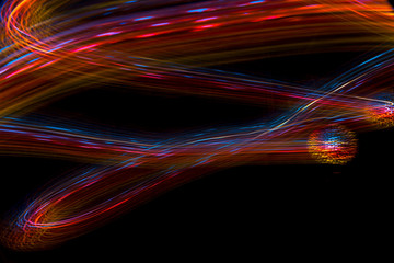 Abstract blurred space comet, multi-colored light lines on a black background.