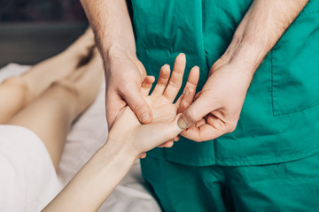 Wrist massage. A male massage therapist puts pressure on a sensitive point on a woman's hand.	