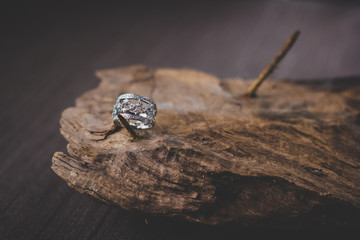A beautiful diamond gold ring on a wooden board. Close-up photography jewelry products.