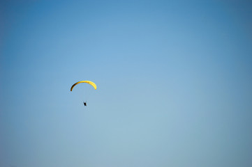 parachutist with yellow wing in the blue sky