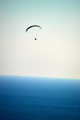 skydiver flying in the white clouds above the blue ocean water