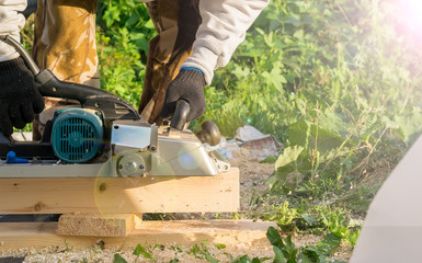 man planing boards with electric tools, chips flying in all directions. Construction, wood processing