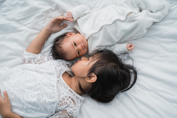 top view of infant baby and girl sibling enjoying together on bed