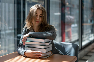 caucasian girl student fell asleep on pile books in institute library