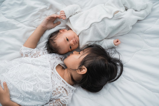 top view of infant baby and girl sibling enjoying together on bed