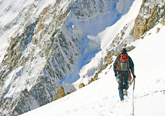 Tourist with a backpack and mountain panorama. Alpinist climber reaches the summit of mountain peak. Climber on the glacier. Success, freedom and happiness, achievement in mountains.