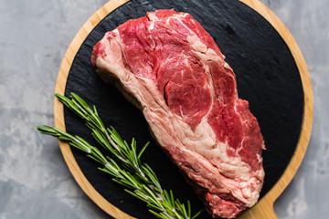 Raw meat beef on a cutting board with rosemary and spices. Top view, flat lay, mockup, copy space. Food concept