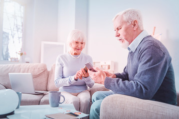 Obraz premium Modern pensioners using their smartphones sitting on sofa at home