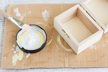 Woman paints on white color a wooden box.