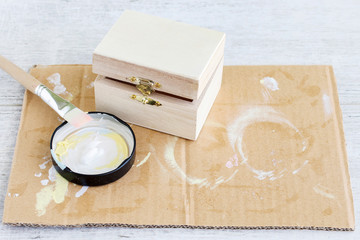 Woman paints on white color a wooden box.