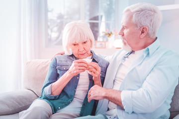 Bearded retired man supporting his wife feeling sick and sneezing
