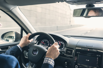 Selective focus of man hands on steering wheel driving a car on the speed highway. View from above