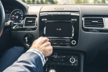 Selective focus of  man using car audio stereo system while driving his car