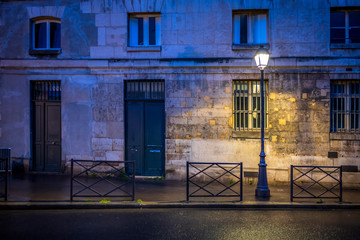 The light of lonely street lamp on the evening street of Paris after the rain