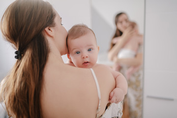 Close up of Caucasian mother holding her loving six months old son. Baby looking at camera with curious facial expression.