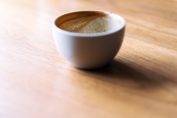 A white mug of hot coffee on wooden table in the morning