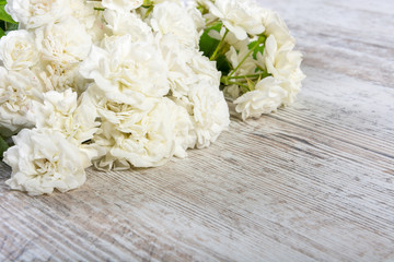 White roses lie on old white boards, close-up. Romantic vintage background with roses for advertising, banner. Side view, Copy space, place for text.
