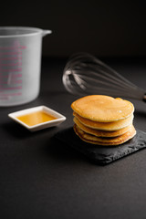 Stack of delicious pancakes with pouring maple syrup on top on dark background. healthy breakfast concept