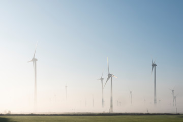 wind turbines in green meadow near aurich in ostfriesland on misty morning in august