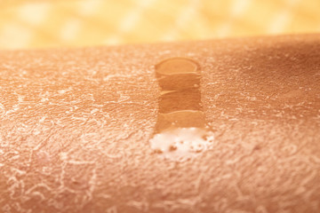A macro view of a drop of moisture on extremely dry skin, sweat coming from pores as person...