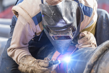 Fototapeta na wymiar Construction worker welding pipes on a heavy site.