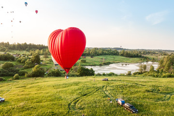 Obraz premium balonem na gorące powietrze czerwone serce nad piękną chmurą w tle wschodu słońca