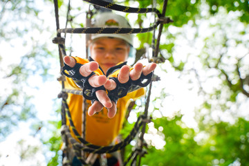 A child in a yellow T-shirt and sportswear is climbing on green trees.