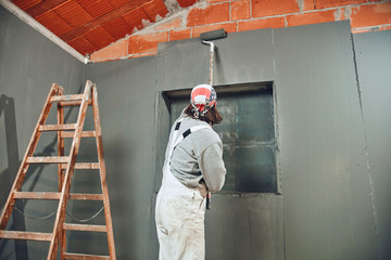 Painter painting walls with a extender roller indoors.