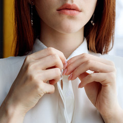 Unrecognizable redhead woman unbuttoning white blouse.