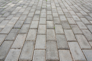 Low angle closeup of old pedestrian pavement surface paved with gray stone bricks