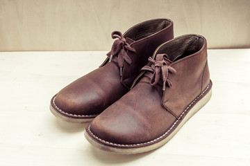Brown stylish boots on wood background,  retro color