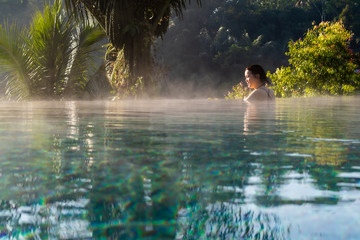 A young woman relaxing in an infinity pool