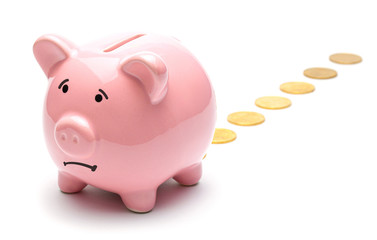 Loss of money. Pink piggy bank losing gold coins isolated on a white background. Bad investment or falling profits