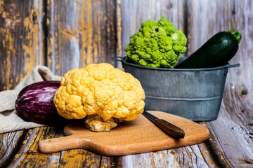Chou-fleur jaune aubergine courgette chou romanesco sur une planche à découper, légumes bio du jardin