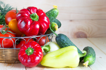 Fresh harvested washed vegetables in wicker basket on wooden table with copy space. Summer harvest.